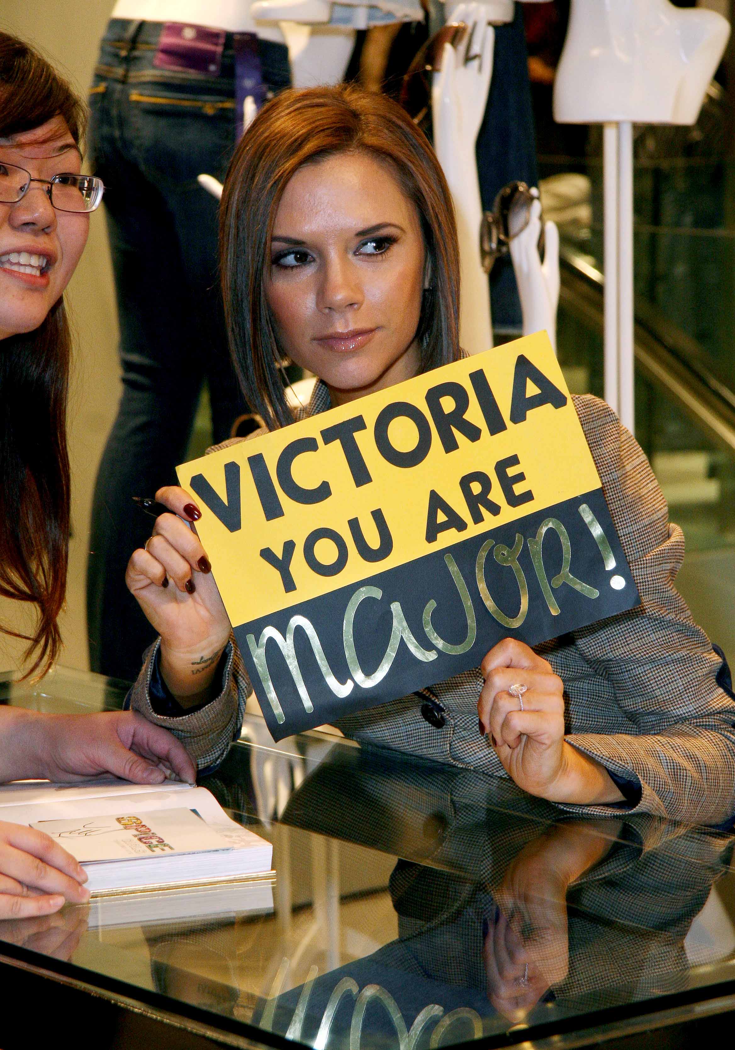 Victoria Beckham holds a sign with her favorite catch phrase while touring Toronto